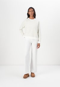 Vit och ljusgrön randig sweatshirt med rund hals, matchad med vita vida byxor och bruna snörskor. Slät textur.