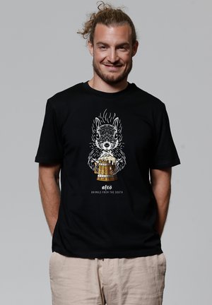 Zwarte katoen t-shirt met een gedetailleerde, gestileerde afbeelding van een eekhoorn die een vat vasthoudt, met tekst die luidt "dieren uit het zuiden."