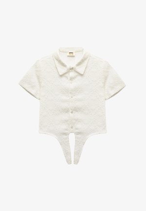 Hvid bluse med korte ærmer og et struktureret diamantmønster. Har en spidse krave og knaplukninger samt et unikt split-hjem-design.