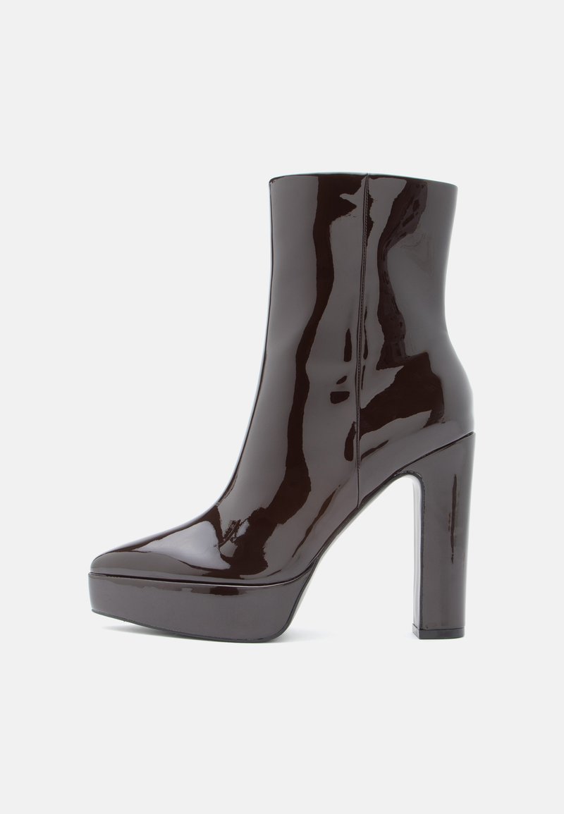 Γυαλιστερό μαύρο μποτάκι έως τον αστράγαλο με ψηλό χοντρό τακούνι και πλατφόρμα. Λείος υφής, στρογγυλή μύτη και κομψή σιλουέτα. Χωρίς ορατά μεταλλικά στοιχεία.