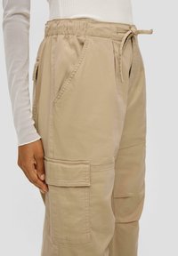 Beige cargo broek gemaakt van een katoenmix, met een elastische tailleband, striksluiting, zijzakken en een patch pocket op het been.