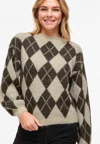 Pull gris clair avec motif argyle marron foncé. Confectionné en tissu tricoté texturé. Doté d'un col rond et de manches longues légèrement bouffantes.
