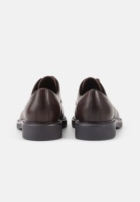 Des chaussures en cuir marron avec une finition lisse, un bout rond et un petit talon en caoutchouc. Présentent un design épuré et simple avec des accents minimaux.
