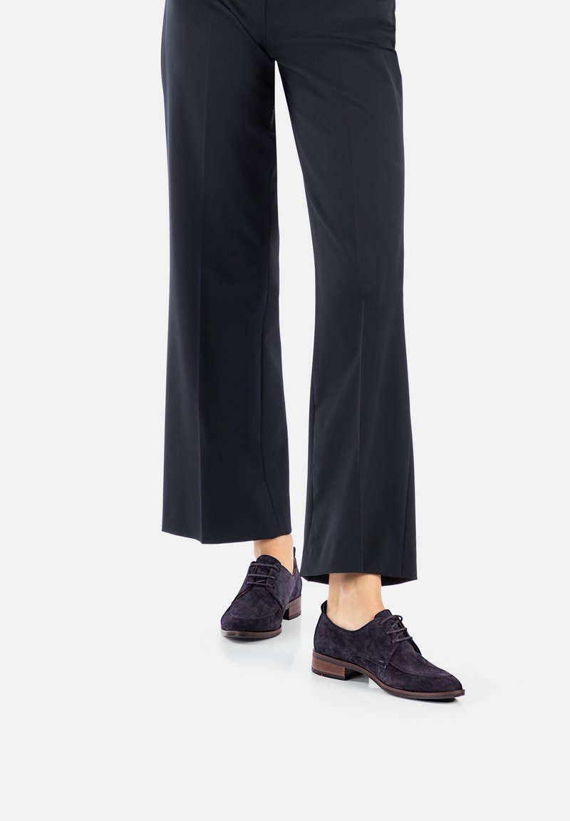 Donkerpaarse suède schoenen met een lage hak, voorzien van vetersluiting en een ronde neus, gecombineerd met brede zwarte broek.