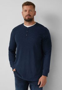 Marineblaue Langarm-Henley-T-Shirt mit einem weißen Kragen, einer Knopfleiste mit drei Knöpfen und einer Tasche am linken Ärmel. Glatte Textur, lockere Passform.