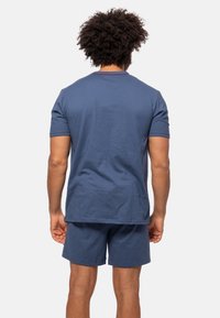 Mørkeblå bomulds t-shirt med korte ærmer og rund hals, parret med matchende shorts. Enkel design, blød tekstur, ingen synlige mønstre eller accenter.