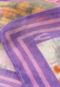 Lehký szalik w kolorach fioletowym i różowym z wzorem; charakteryzuje się delikatnym połyskiem, cienką teksturą oraz szytymi krawędziami z geometrycznymi wzorami.