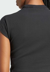 Black ribbed crop top featuring short sleeves and a rounded neckline, made of a stretchy fabric for a fitted look.
