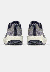 Grijze sportschoenen met een gestructureerd ontwerp, geaccentueerd door paarse en marineblauwe details, voorzien van een stevige witte zool en een patroon op de hiel.