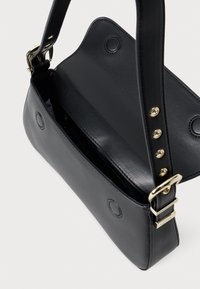 Geantă de umăr din piele neagră cu o textură netedă, având un capac superior, accesorii aurii și o curea ajustabilă unică. Pocket interior vizibil.