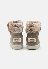 Bottes chelsea en suède beige avec une douce doublure en fausse fourrure, dotées d'une semelle en caoutchouc grise et d'accents beige, conçues pour le confort et la chaleur.