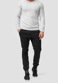 Gray long-sleeve fitted shirt, black tapered pants with side pockets, and black athletic shoes with white soles. Simple and solid colors.