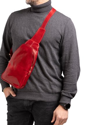 Borsa a tracolla rossa in pelle con finitura liscia, tracolla regolabile e tasca laterale con zip, indossata su un pullover grigio con collo alto.