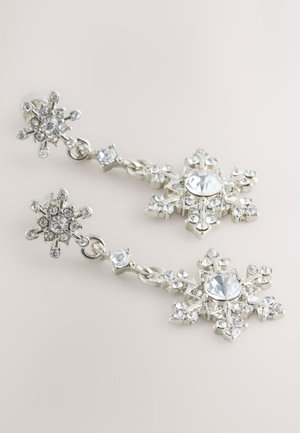 Boucles d'oreilles pendantes en ton argent ornées de motifs flocons de neige, serties de multiples strass clairs, présentant des détails et une texture complexes.