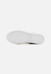 Weiße Sneaker-Sohle mit einem strukturierten Muster und Logo in der Mitte. Glatte Kanten mit einer leichten Kurve an der Zehe und der Ferse.