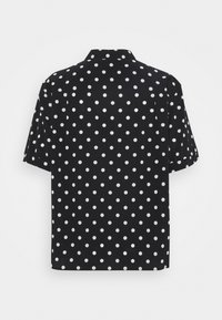 Short-sleeve shirt in black fabric featuring white polka dots. Buttoned collar and relaxed fit. Smooth texture with a uniform pattern.