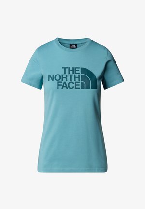 Jasnoniebieska koszulka wykonana z bawełny, z wyrazistym ciemnoniebieskim logo "THE NORTH FACE" na środku. Krótkie rękawy i okrągły dekolt.