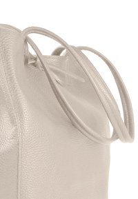 Sac en cuir gris clair avec une surface texturée, une forme arrondie et deux longues poignées lisses. Doté d'un design supérieur froncé.