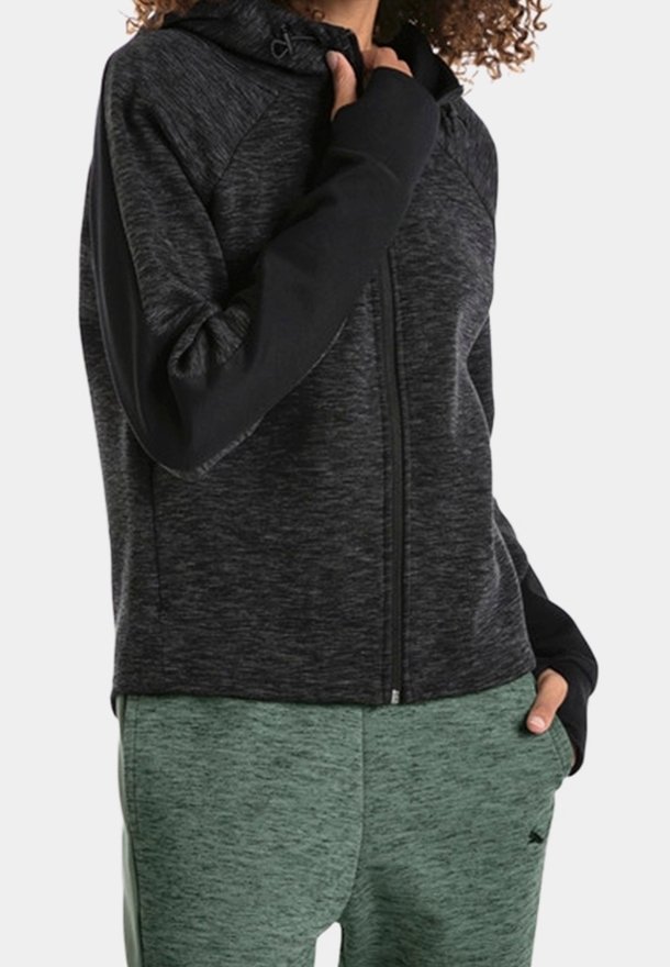 Sudadera con cremallera en negro y gris, con un acabado texturizado y mangas raglán. Combinada con pantalones jogger verdes, que cuentan con una cinturilla ajustable y un patrón sutil.