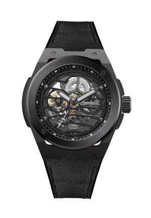 Montre squelette noire avec un cadran rond mettant en valeur des rouages mécaniques complexes, bracelet en cuir texturé et accents argentés.