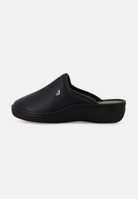 Scarpa nera in pelle slip-on con punta rotonda, profilo basso e superficie texturizzata. Presenta un sottile dettaglio logo vicino al bordo superiore.