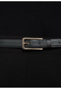 Cintura in pelle nera con fibbia in metallo dorato, caratterizzata da una superficie liscia e un design classico. Adatta per vari completi.