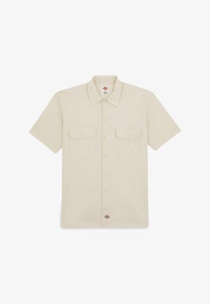 Camisa corta de algodón en color beige claro, con mangas cortas, parte delantera abotonada, dos bolsillos de solapa y una etiqueta de marca en la parte inferior izquierda.
