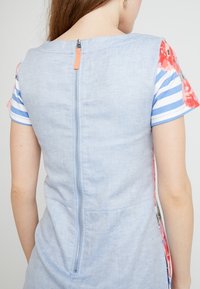 Blue linen dress with floral patterned sleeves and a back zipper. The fabric is textured, and the design features stripes and solid colors.