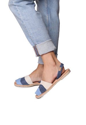 Colorful sandals featuring a mix of light blue, dark blue, and beige leather. Open-toe design with a back strap and stitched accents.
