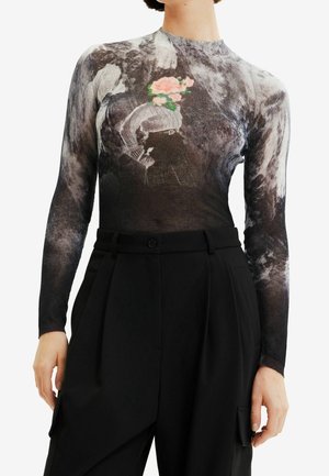 Haut moulant à manches longues avec un motif abstrait noir, blanc et gris et un graphique central d'une femme avec une fleur à la place de la tête, associé à un pantalon noir.