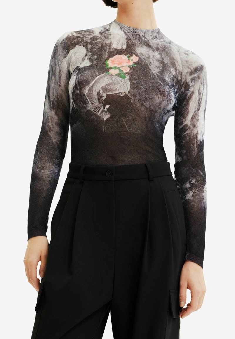 Haut moulant à manches longues avec un motif abstrait noir, blanc et gris et un graphique central d'une femme avec une fleur à la place de la tête, associé à un pantalon noir.