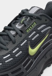 Μαύρο αθλητικό παπούτσι Nike Max Air 2006 με λογότυπο νέον κίτρινο και ανακλαστικές ασημένιες λεπτομέρειες, με διάτρητο ύφασμα και δερμάτινες λεπτομέρειες.