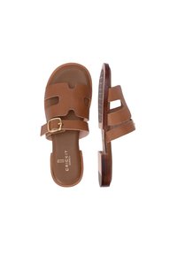 Bruine leren sleehak sandalen met open zijkanten, een verstelbare enkelband met een gouden gesp en een houten zool met een gestructureerde onderkant.