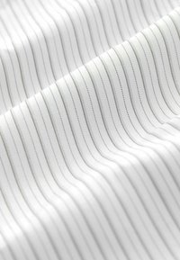 Tissu blanc avec de fines rayures verticales grises, offrant une texture lisse et un léger éclat, créant un effet de superposition subtil.