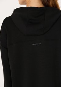 Zwarte hoodie met een zachte textuur, verstelbare capuchon en zichtbaar "ENDURANCE" logo in het grijs op de achterkant. Eenvoudig en functioneel ontwerp.