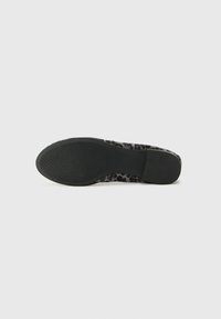 Sneaker nera con suola testurizzata, caratterizzata da una tomaia con stampa leopardata. Il design è basse e presenta una finitura liscia con accenti sottili.