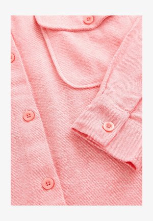 Camicia a bottoni color corallo con texture a spina di pesce, colletto a punta e bottoni abbinati. Dettagli di cucitura visibili sui polsini.