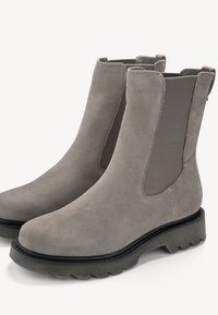Bottines en daim gris avec panneaux élastiques sur les côtés, bout rond et semelle en caoutchouc texturée avec un détail de crampons prononcé.