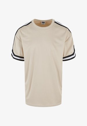 Camiseta de malla beige con detalles en franjas negras y blancas en las mangas. Presenta un cuello redondo y un diseño de corte holgado para mayor comodidad.