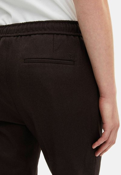 Bruine joggers met elastische tailleband en een achterzak, met een subtiele textuur en een klein merkaccent. Het ontwerp is slim-fit.