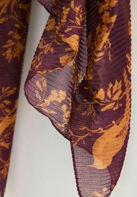 Durchsichtiger Schal mit geripptem Muster in tiefem Burgunderrot und einem orangefarbenen Blumenmuster. Die Kanten sind sanft gewellt.