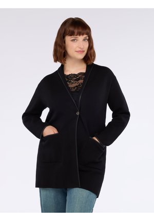 Schwarze Strickjacke mit Schalkragen, Knopfverschluss und zwei vorderen Taschen. Mit einem strukturierten Spitzen-Detail darunter. Weicher Stoff, lockere Passform.