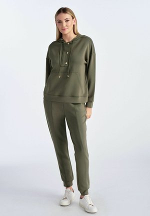 Oliwkowa bluza z kapturem z przednią kieszenią, sznurkiem przy kapturze i złotymi akcentami, zestawiona z pasującymi oliwkowymi dresami z detalami szwów.