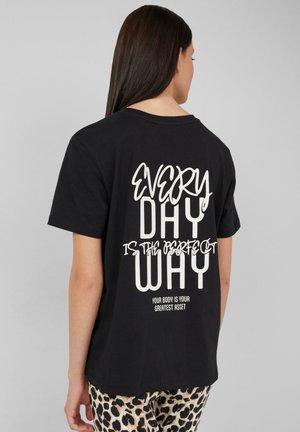T-shirt en coton noir avec un design de texte blanc audacieux au dos : "CHAQUE JOUR EST LE MEILLEUR" avec une phrase secondaire en dessous.