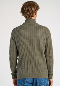 Olive green knitted sweater, featuring a ribbed texture and high collar. Fitted design with long sleeves and a straight hem.
