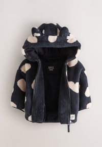 Veste zippée doublée en polaire avec une base bleu marine foncé ornée de grands pois crème, une capuche avec des oreilles d'ours et une texture douce.