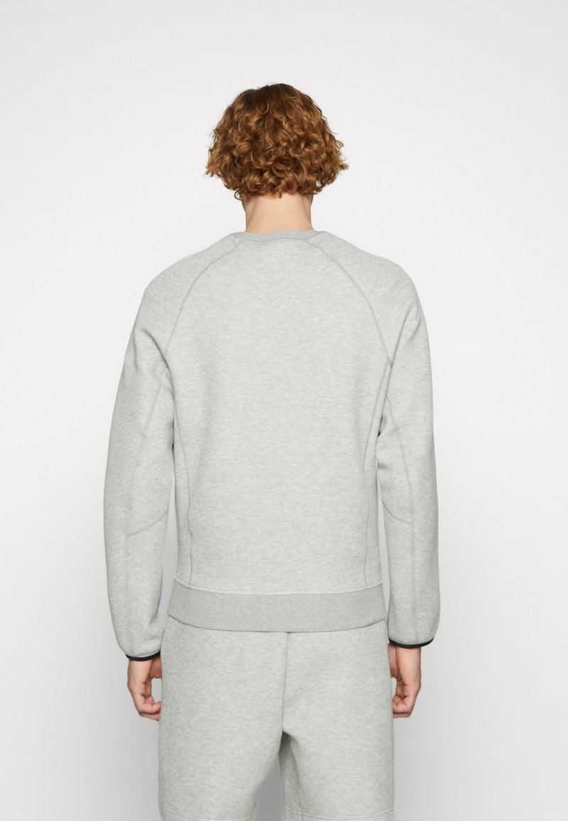 Sweatshirt gris avec un col rond, des poignets et un ourlet côtelés. Doté de manches raglan et d'une texture douce, présenté vu de dos.