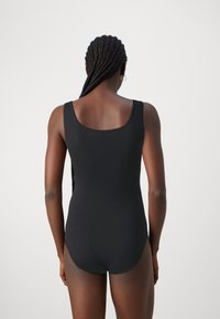 Bañador negro de una sola pieza con espalda en forma de scoop, hecho de un tejido suave, que cuenta con tirantes anchos y un diseño ajustado.