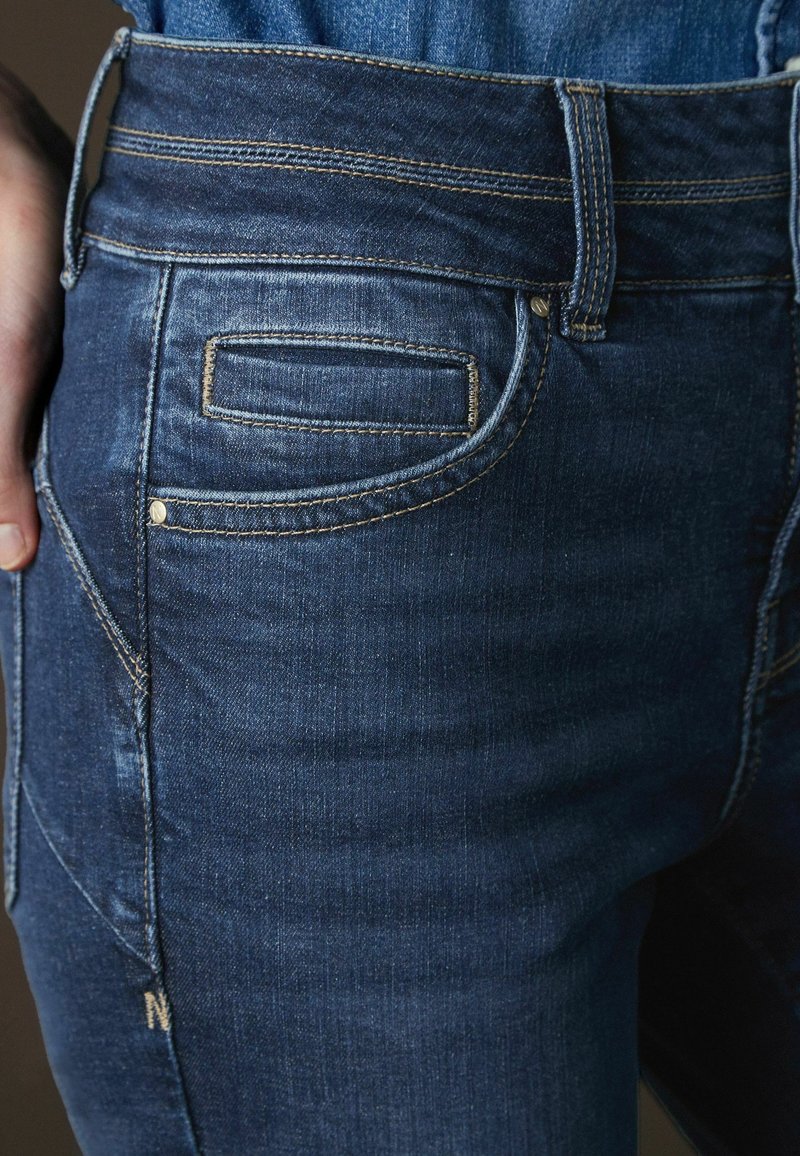 Mörkblå denimjeans med hög midja, fem fickor, kontrasterande sömmar och en subtilt urtvättad textur på tyget.