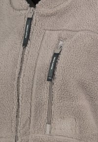 Fleecejacke in weichem Grau mit strukturierter Oberfläche. Verfügt über zwei Reißverschlusstaschen, langlebige Beschläge und ein gesticktes Logo auf der Vorderseite.